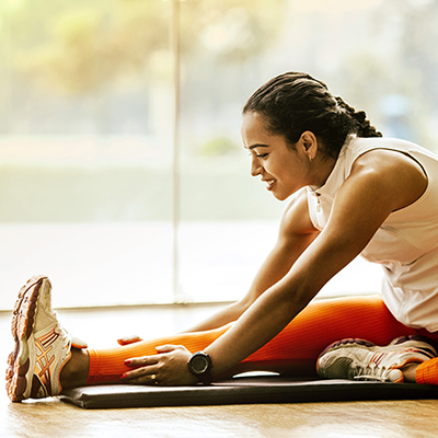 woman on ground stretching in white shirt and orange leggings